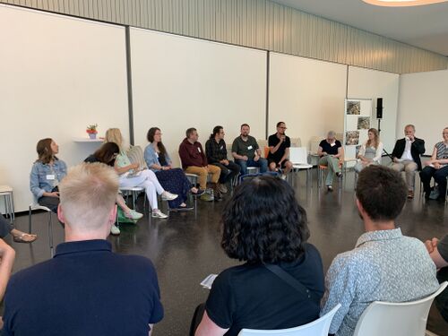 Teilnehmende sitzen im Kreis und diskutieren zu Zukunftsbildern.