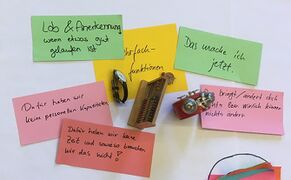 Auf dem Foto sind wenige beschriebene rote und grüne Moderationskarten zu sehen. Zwischen den Moderationskarten liegen Uhren und ein gelber Zettel mit der Aufschrift "Mehrfachfunktionen".